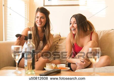 Two young women sitting on sofa, drinks and snacks on table View Large Photo Image Stock Photo - Two young women sitting on sofa, drinks and snacks on table. Fotosearch
