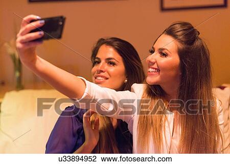 Two young women, taking self portrait using martphone View Large Photo Image Stock Image - Two young women, taking self portrait using martphone. Fotosearch