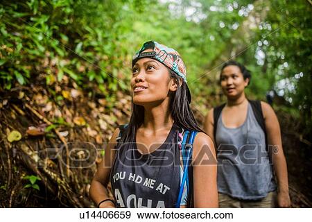 Stock Photo - Two young women tourists strolling in jungle at Manoa Falls, Oahu, Hawaii, USA. Fotosearch