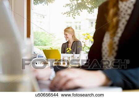 Picture - Two young women using laptops in cafe. Fotosearch