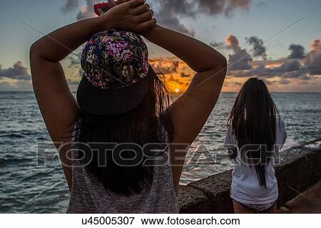 Two young women watching sunrise, Kaaawa beach, Oahu, Hawaii, USA View Large Photo Image Stock Photo - Two young women watching sunrise, Kaaawa beach, Oahu, Hawaii, USA. Fotosearch