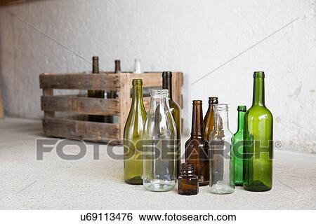 Stock Photograph - Variety of empty bottles and wooden crate in garage. Fotosearch