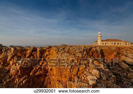 Stock Image - View of Punta Nati lighthouse on sunlit cliff, Menorca, Spain. Fotosearch