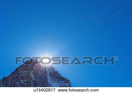 Stock Photo - View of rugged mountain peak, sunlight and blue sky, Mont Blanc massif, Graian Alps, France. Fotosearch