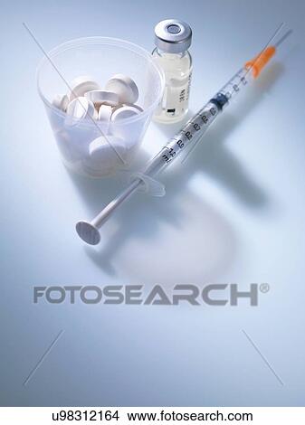 Picture - White tablets in plastic measuring cup with vial and syringe. Fotosearch