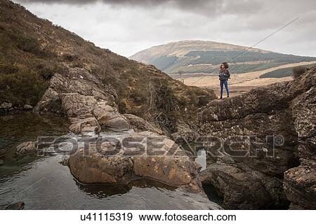 Woman standing on rocks, Fairy Pools, Isle of Skye, Hebrides, Scotland View Large Photo Image Stock Photo - Woman standing on rocks, Fairy Pools, Isle of Skye, Hebrides, Scotland. Fotosearch