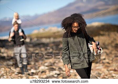 Picture - Woman walking with man and child in background. Fotosearch
