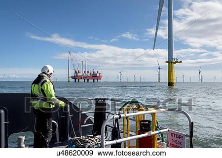 Worker looking out from ship to offshore wind farm and construction ship View Large Photo Image Stock Photo - Worker looking out from ship to offshore wind farm and construction ship. Fotosearch
