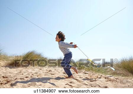 Stock Photo - Young boy flying kite on beach. Fotosearch