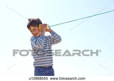 Stock Photography - Young boy, holding cup and string telephone to ear. Fotosearch