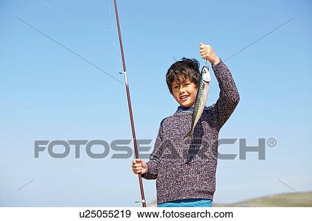 Young boy holding up fishing rod and fish View Large Photo Image Stock Photo - Young boy holding up fishing rod and fish. Fotosearch