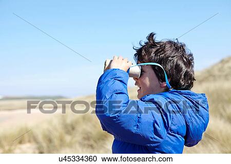 Young boy on beach, looking through pretend binoculars View Large Photo Image Stock Image - Young boy on beach, looking through pretend binoculars. Fotosearch