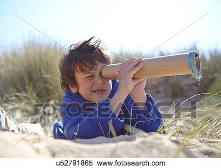 Young boy on beach, looking through pretend telescope View Large Photo Image Stock Photography - Young boy on beach, looking through pretend telescope. Fotosearch