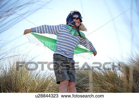 Young boy on beach, wearing fancy dress, pretending to fly View Large Photo Image Stock Image - Young boy on beach, wearing fancy dress, pretending to fly. Fotosearch