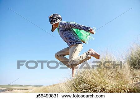 Young boy on beach, wearing fancy dress, pretending to fly View Large Photo Image Stock Image - Young boy on beach, wearing fancy dress, pretending to fly. Fotosearch