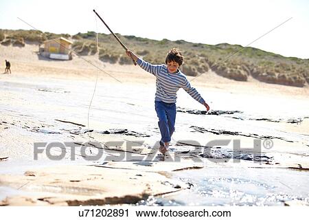Young boy running along sand with stick View Large Photo Image Stock Image - Young boy running along sand with stick. Fotosearch