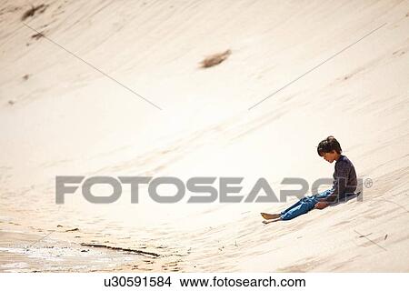 Picture - Young boy sitting on sandy hill. Fotosearch