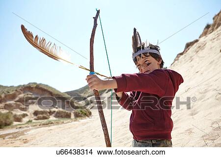 Young boy wearing fancy dress, holding home-made bow and arrow View Large Photo Image Picture - Young boy wearing fancy dress, holding home-made bow and arrow. Fotosearch