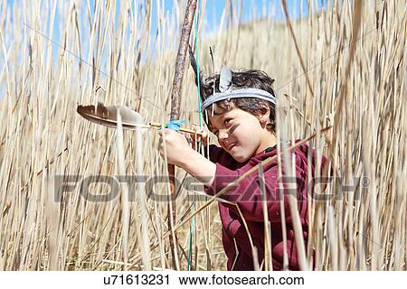 Stock Image - Young boy wearing fancy dress, holding home-made bow and arrow. Fotosearch