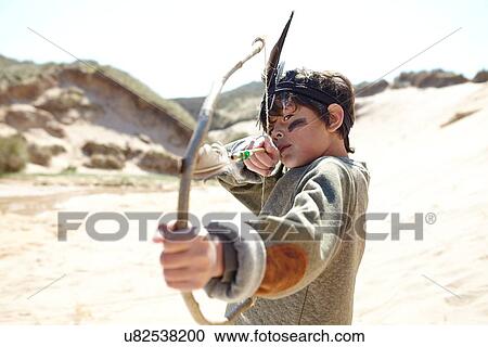 Stock Image - Young boy wearing fancy dress, holding home-made bow and arrow. Fotosearch