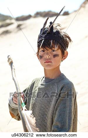 Stock Image - Young boy wearing fancy dress, holding home-made bow and arrow. Fotosearch