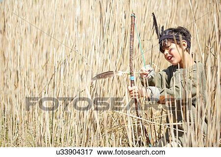 Stock Photo - Young boy wearing fancy dress, holding home-made bow and arrow. Fotosearch
