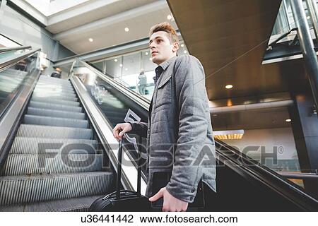 Young businessman commuter on escalator holding suitcase handle. View Large Photo Image Stock Image - Young businessman commuter on escalator holding suitcase handle.. Fotosearch