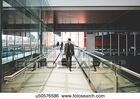 Stock Photograph - Young businessman commuter on railway concourse with suitcase.. Fotosearch
