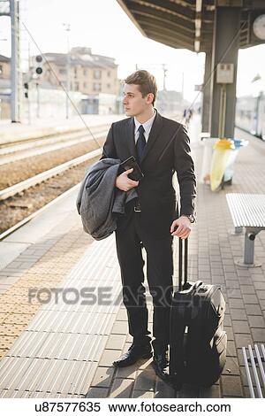 Young businessman commuter standing on railway platform with suitcase. View Large Photo Image Stock Photography - Young businessman commuter standing on railway platform with suitcase.. Fotosearch
