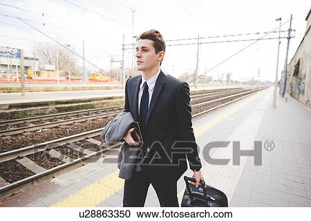 Young businessman commuter walking along railway platform with suitcase. View Large Photo Image Stock Image - Young businessman commuter walking along railway platform with suitcase.. Fotosearch