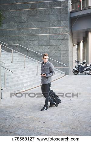 Young businessman commuter walking with suitcase. View Large Photo Image Stock Photo - Young businessman commuter walking with suitcase.. Fotosearch