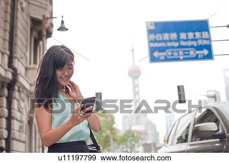 Young businesswoman, using smartphone, outdoors, Shanghai, China View Large Photo Image Stock Photo - Young businesswoman, using smartphone, outdoors, Shanghai, China. Fotosearch