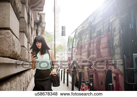 Young businesswoman, using smartphone, outdoors, Shanghai, China View Large Photo Image Stock Photo - Young businesswoman, using smartphone, outdoors, Shanghai, China. Fotosearch