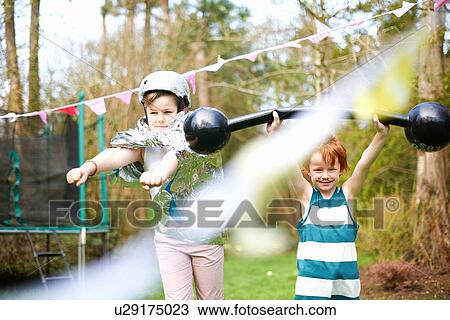 Stock Image - Young children wearing fancy dress, playing in garden. Fotosearch