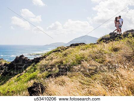 Stock Photograph - Young couple kissing on cliff top on Makapuu coast path, Oahu, Hawaii, USA. Fotosearch