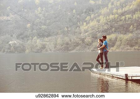 Picture - Young couple looking out from pier at Lake Mergozzo, Verbania, Piemonte, Italy. Fotosearch