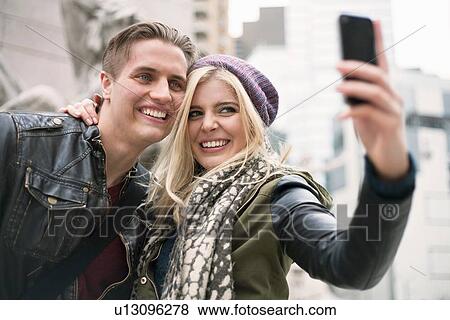 Stock Photo - Young couple posing for smartphone selfie on street, New York, USA. Fotosearch