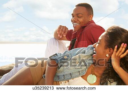 Stock Image - Young couple relaxing together, lying on side, smiling. Fotosearch