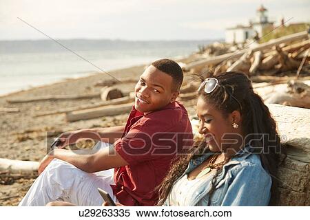 Young couple sitting together on beach smiling View Large Photo Image Stock Photography - Young couple sitting together on beach smiling. Fotosearch