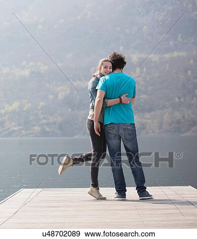 Young couple standing hugging on pier at Lake Mergozzo, Verbania, Piemonte, Italy View Large Photo Image Stock Photo - Young couple standing hugging on pier at Lake Mergozzo, Verbania, Piemonte, Italy. Fotosearch