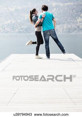 Young couple standing on one leg on pier at Lake Mergozzo, Verbania, Piemonte, Italy View Large Photo Image Stock Image - Young couple standing on one leg on pier at Lake Mergozzo, Verbania, Piemonte, Italy. Fotosearch
