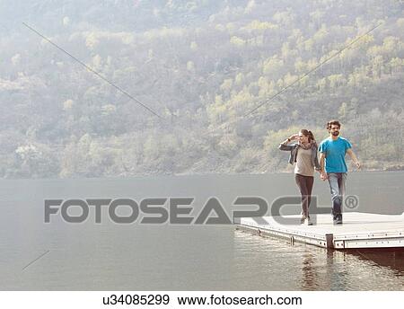 Young couple strolling on pier at Lake Mergozzo, Verbania, Piemonte, Italy View Large Photo Image Stock Photo - Young couple strolling on pier at Lake Mergozzo, Verbania, Piemonte, Italy. Fotosearch