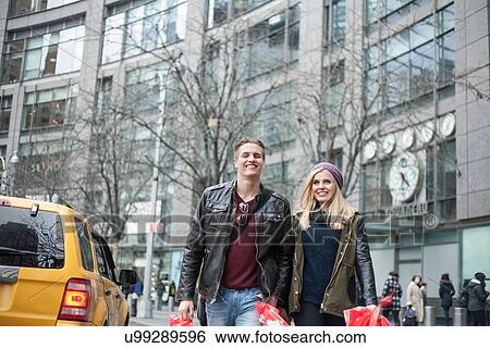 Young couple strolling with shopping bags on street, New York, USA View Large Photo Image Stock Photograph - Young couple strolling with shopping bags on street, New York, USA. Fotosearch
