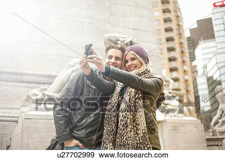 Stock Photo - Young couple taking smartphone selfie on street, New York, USA. Fotosearch