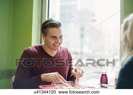 Young couple talking whist eating lunch in cafe View Large Photo Image Stock Image - Young couple talking whist eating lunch in cafe. Fotosearch