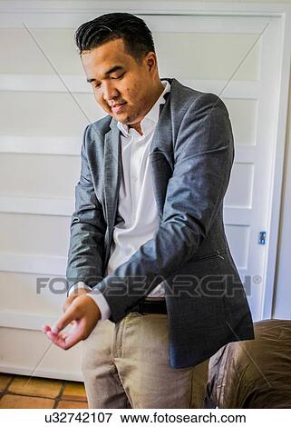 Young man adjusting sleeves whilst getting ready View Large Photo Image Stock Photo - Young man adjusting sleeves whilst getting ready. Fotosearch