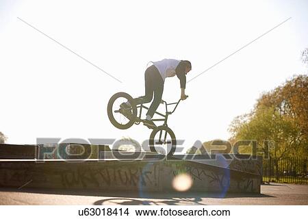 Young man doing stunt on bmx at skatepark, rear view View Large Photo Image Picture - Young man doing stunt on bmx at skatepark, rear view. Fotosearch