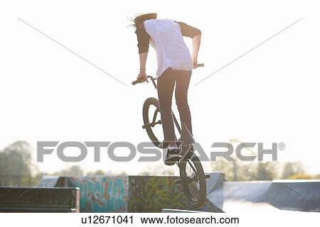 Young man doing stunt on bmx at skatepark, rear view View Large Photo Image Stock Image - Young man doing stunt on bmx at skatepark, rear view. Fotosearch
