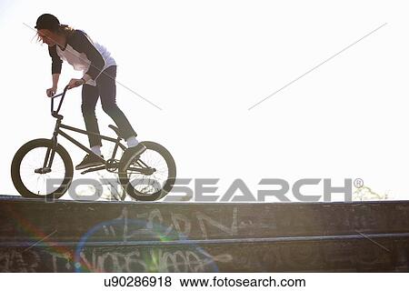 Stock Photo - Young man doing stunt on bmx at skatepark. Fotosearch