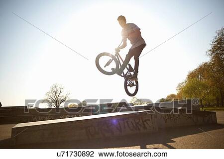 Young man, in mid air, doing stunt on bmx at skatepark View Large Photo Image Stock Image - Young man, in mid air, doing stunt on bmx at skatepark. Fotosearch